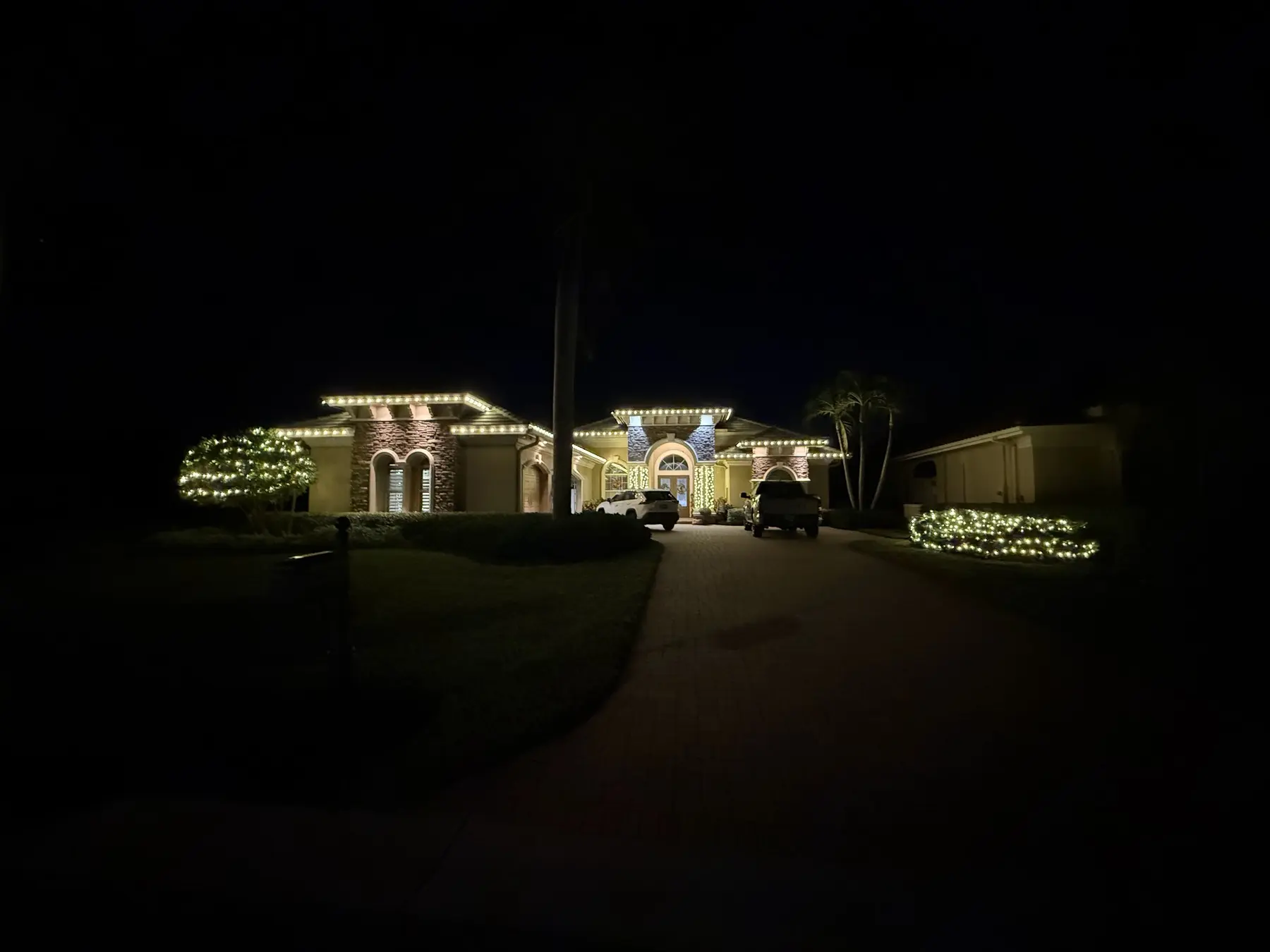 Property at night with professional holiday roofline lighting and lit landscaping